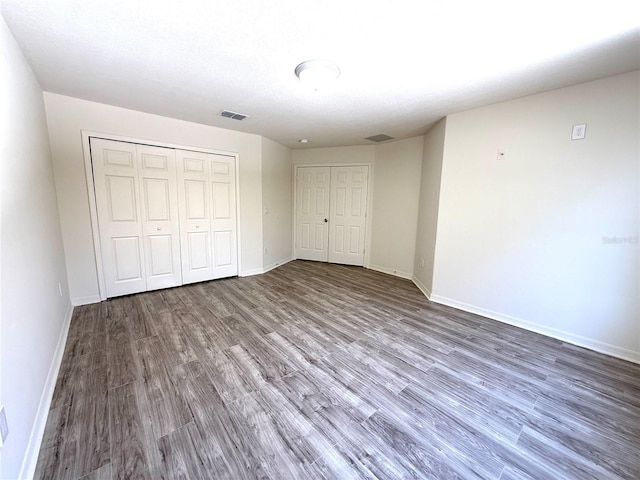 unfurnished bedroom featuring wood finished floors, visible vents, and baseboards