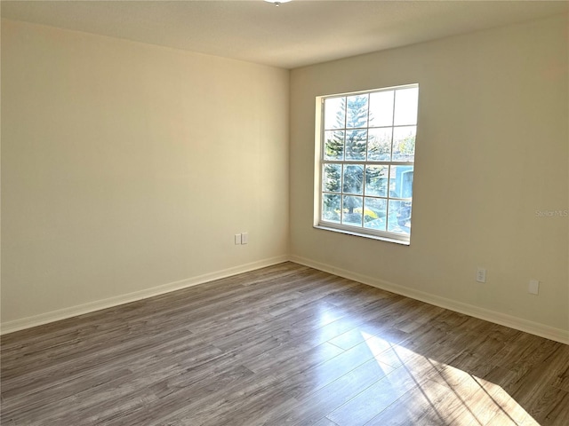 spare room with dark wood finished floors and baseboards