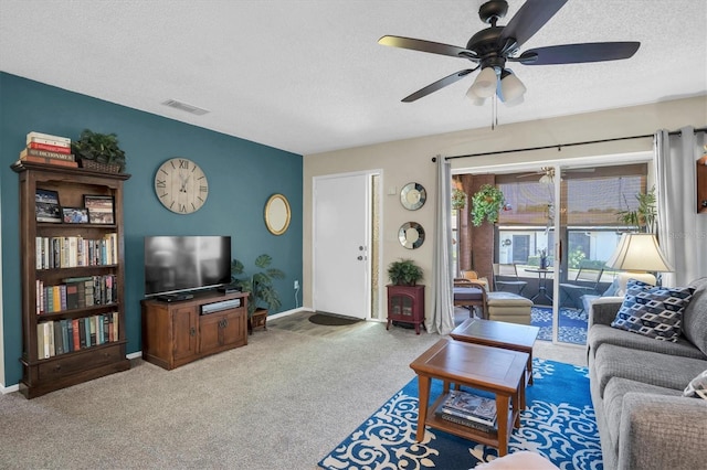 carpeted living room featuring ceiling fan and a textured ceiling