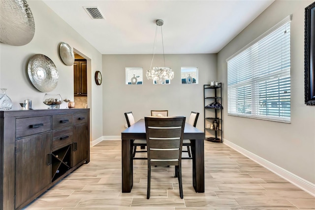 dining area with light hardwood / wood-style floors and a notable chandelier