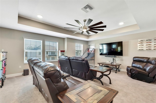 living room with a tray ceiling, light carpet, and ceiling fan