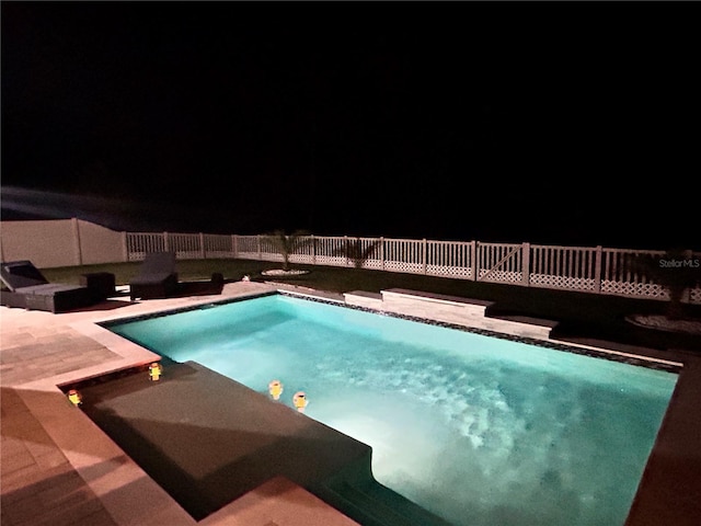 view of pool at twilight