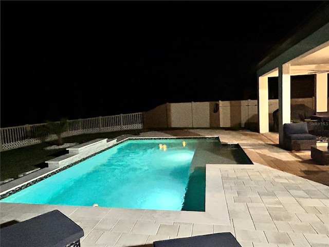 pool at night featuring a patio