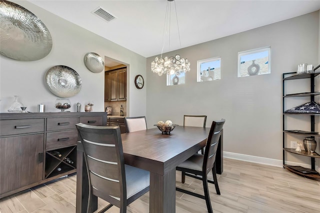 dining space with light wood-type flooring and a notable chandelier