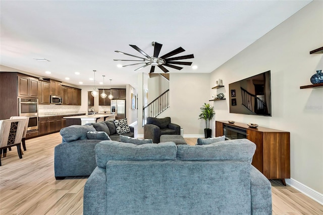 living room with ceiling fan, light hardwood / wood-style floors, and sink