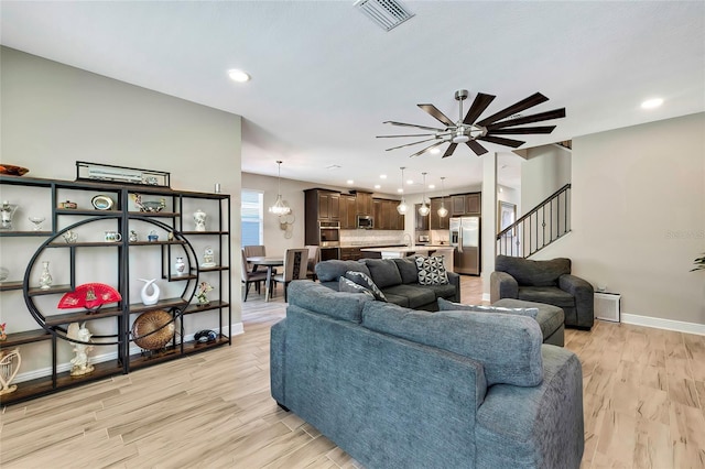 living room featuring light hardwood / wood-style flooring and ceiling fan with notable chandelier