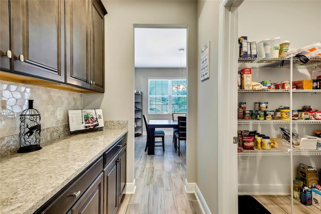 interior space featuring light wood-type flooring, dark brown cabinetry, and backsplash