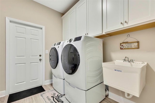 laundry room featuring cabinets, light hardwood / wood-style flooring, washer and clothes dryer, and sink