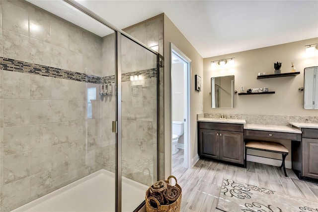 bathroom with vanity, toilet, a shower with door, and plenty of natural light