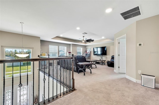 interior space featuring a tray ceiling, light carpet, and a healthy amount of sunlight