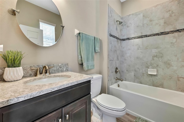 full bathroom featuring vanity, hardwood / wood-style flooring, toilet, and tiled shower / bath