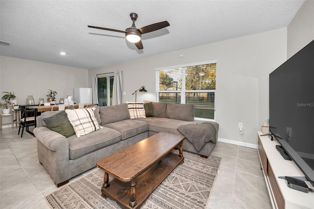 living room featuring ceiling fan, light tile patterned floors, and a textured ceiling