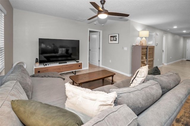 living room featuring ceiling fan and a textured ceiling