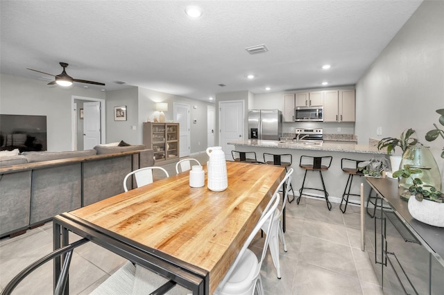 dining space featuring light tile patterned floors, a textured ceiling, ceiling fan, and sink