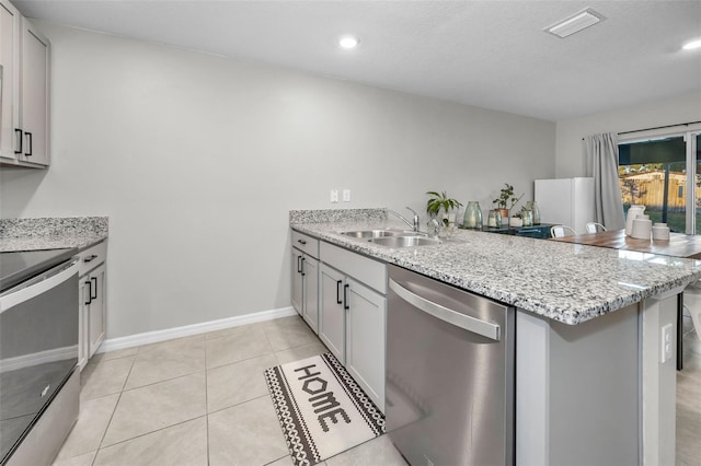 kitchen with kitchen peninsula, appliances with stainless steel finishes, sink, light tile patterned floors, and white cabinetry