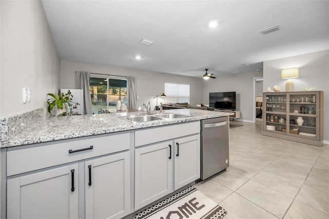 kitchen featuring light stone countertops, a textured ceiling, ceiling fan, sink, and dishwasher