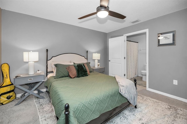 carpeted bedroom with ensuite bath and ceiling fan