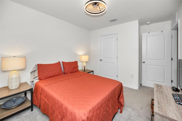 bedroom featuring light colored carpet and a textured ceiling