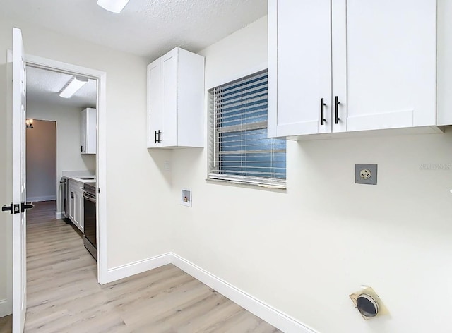 clothes washing area featuring cabinets, hookup for an electric dryer, light hardwood / wood-style flooring, hookup for a washing machine, and a textured ceiling