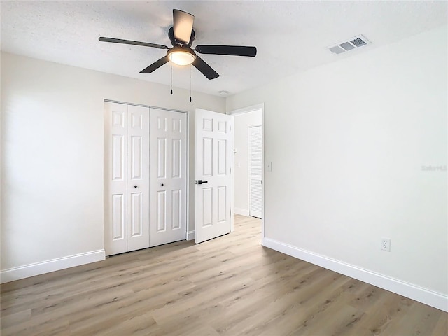 unfurnished bedroom with light wood-type flooring, a closet, and ceiling fan