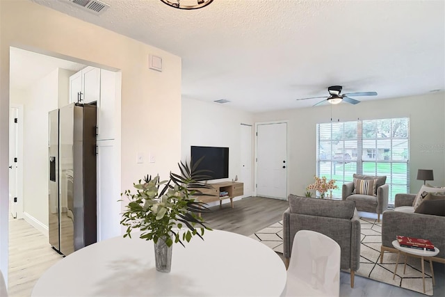 dining area with ceiling fan, a textured ceiling, and light hardwood / wood-style flooring