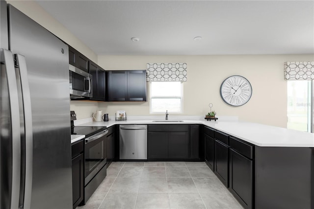 kitchen with kitchen peninsula, sink, light tile patterned flooring, and stainless steel appliances