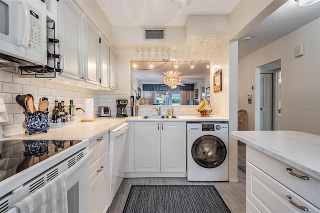 kitchen with white cabinetry, washer / dryer, white appliances, and sink