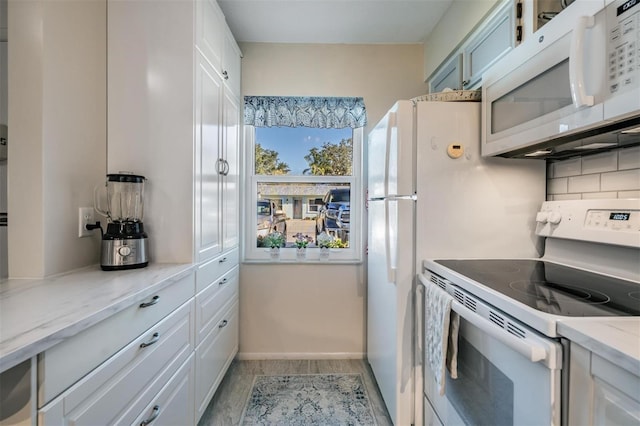 kitchen featuring white cabinetry, light stone counters, white appliances, and backsplash