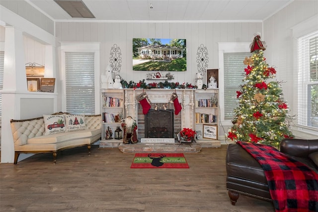 living room with dark hardwood / wood-style floors, crown molding, and wooden walls