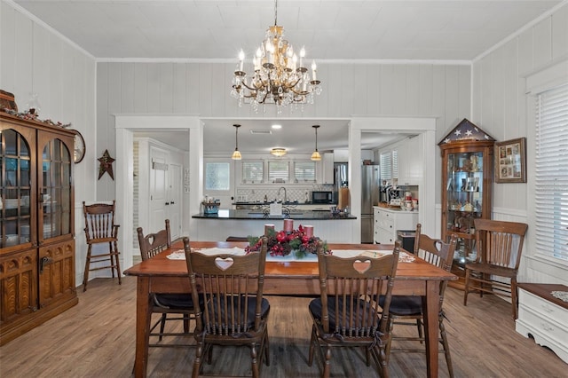 dining room with wood-type flooring, ornamental molding, and wood walls