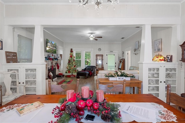 dining area featuring ceiling fan, crown molding, wood-type flooring, and wood walls