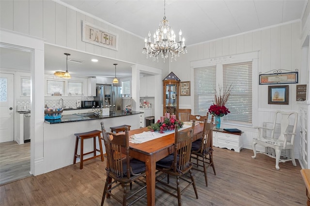 dining room with plenty of natural light, sink, wood-type flooring, and crown molding