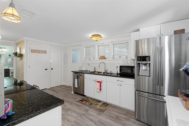 kitchen featuring white cabinets, sink, light wood-type flooring, appliances with stainless steel finishes, and decorative light fixtures