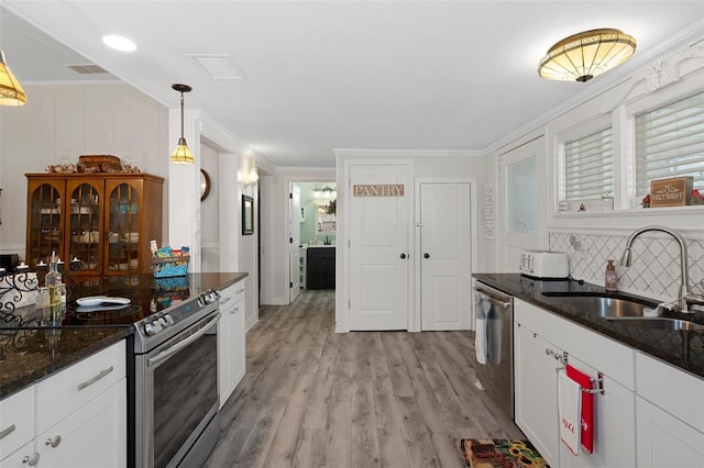 kitchen with sink, stainless steel appliances, tasteful backsplash, decorative light fixtures, and white cabinets