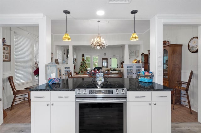 kitchen with hanging light fixtures, electric range, dark stone countertops, light wood-type flooring, and white cabinetry