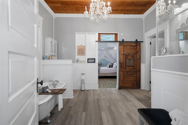 interior space with wooden ceiling, a barn door, ornamental molding, wood-type flooring, and a chandelier