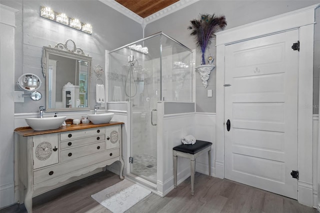 bathroom with vanity, wood-type flooring, a shower with door, and ornamental molding