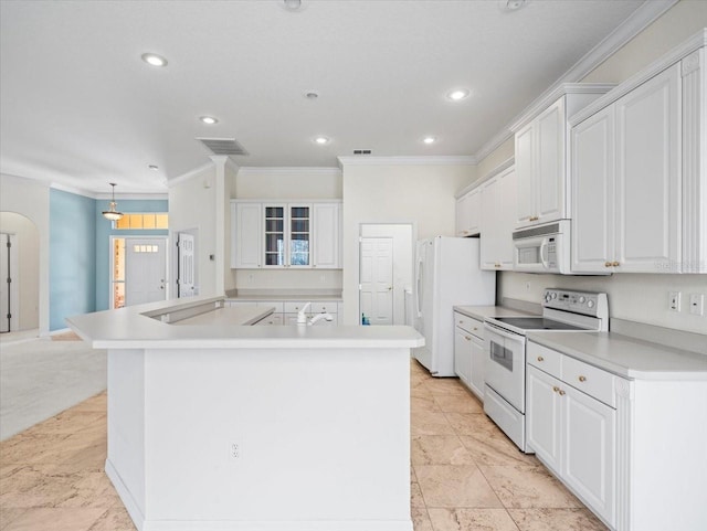 kitchen featuring white appliances, a spacious island, white cabinetry, and ornamental molding