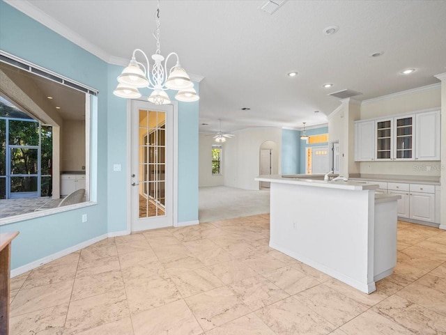 kitchen with white cabinetry, crown molding, an island with sink, decorative light fixtures, and ceiling fan with notable chandelier