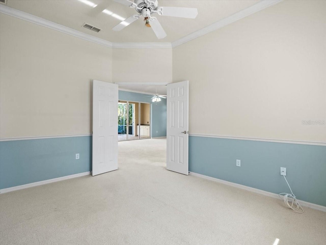 empty room featuring ceiling fan, crown molding, and light carpet