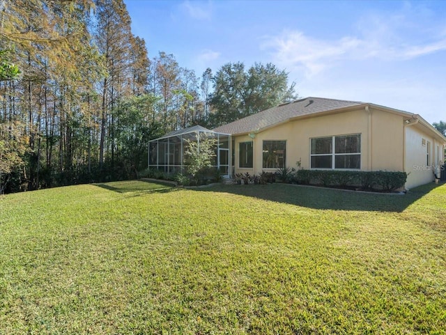 rear view of house with glass enclosure and a yard