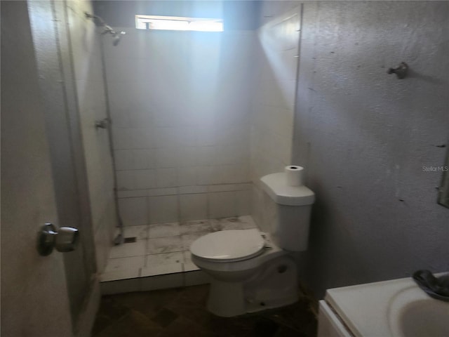 bathroom featuring a tile shower and toilet