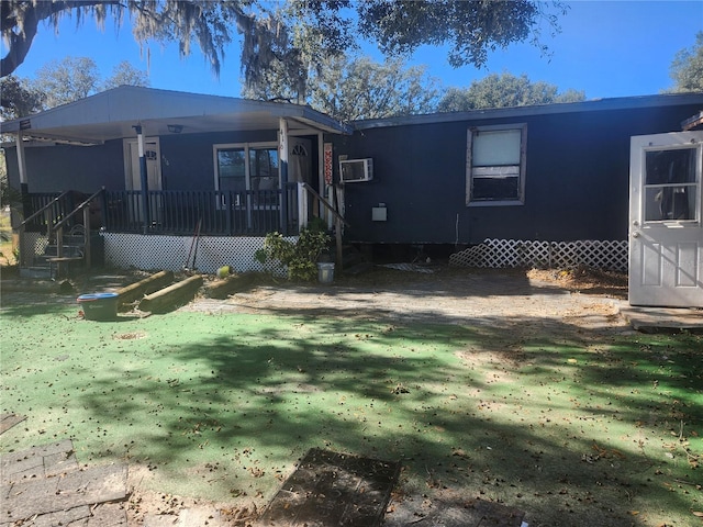 rear view of house featuring a wall mounted AC, a yard, and covered porch