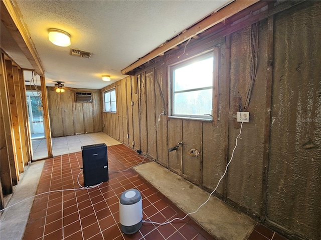 basement featuring a wall unit AC, a wealth of natural light, dark tile patterned floors, and wood walls