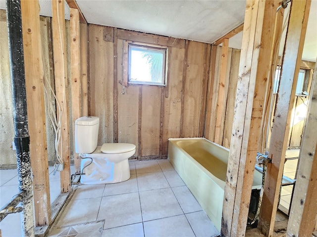 bathroom with tile patterned floors, toilet, and a tub