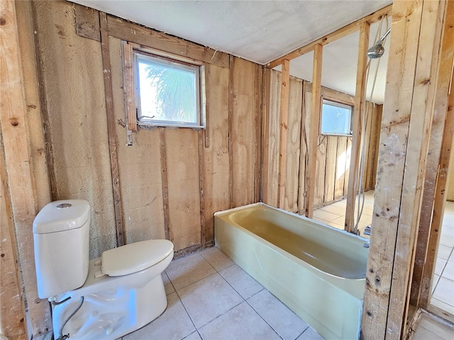 bathroom with tile patterned flooring, a bathing tub, and toilet