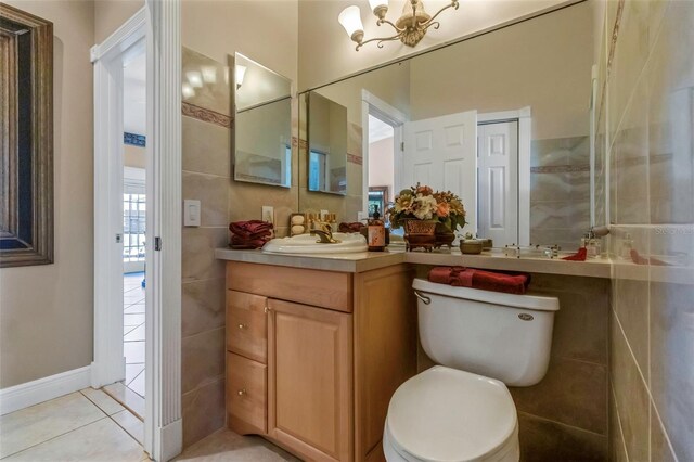 bathroom featuring tile patterned floors, vanity, toilet, and tile walls