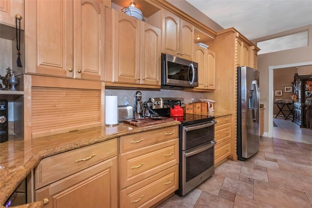 kitchen with light stone countertops, light brown cabinetry, stainless steel appliances, and tasteful backsplash