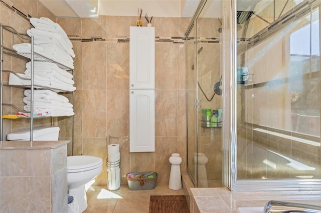 bathroom featuring tile patterned floors, toilet, tile walls, and walk in shower