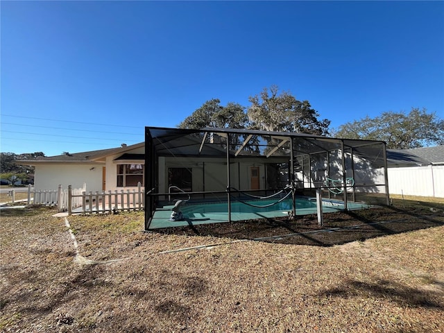 rear view of property with a fenced in pool and glass enclosure